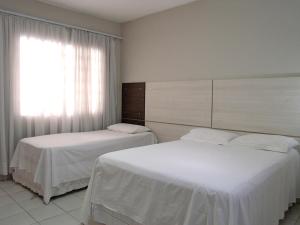 two beds in a hotel room with a window at Hotel Curitiba Campo Comprido in Curitiba