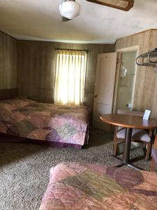 Cette chambre comprend 2 lits et une table. dans l'établissement Coronado West Motel, à Lindsborg
