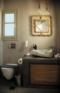 a bathroom with a sink and a toilet and a mirror at CAPE 9 Villas & Suites in Akrotiri