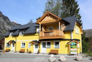 een geel gebouw met een houten balkon bij Ferienwohnungen ARIKOGEL Bad Goisern in Bad Goisern