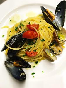 a white plate of pasta with mussels and tomatoes at Hotel Della Baia in Portovenere
