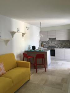 a living room with a yellow couch and a kitchen at Scrigno in Budoni