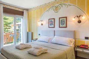 a bedroom with a bed with two towels on it at Hotel Miralago Wellness - Adults Only in Molveno
