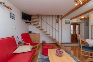 a living room with a red couch and a staircase at Stone house Ernest in Trogir