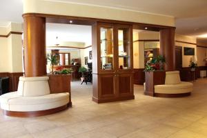 um lobby com duas cadeiras brancas num hotel em Hotel Valentino em Acqui Terme