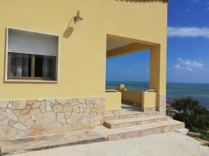 a yellow house with stairs leading to the ocean at Villa Fiorella in Sciacca
