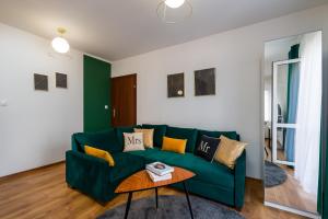a living room with a green couch and a table at Sleepway Apartments- Green Dream in Poznań