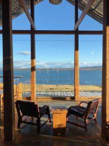 a dining room table with chairs in front of a large body of water at Hotel Simple Patagonia in Puerto Natales