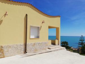 a yellow house with the ocean in the background at Villa Fiorella in Sciacca
