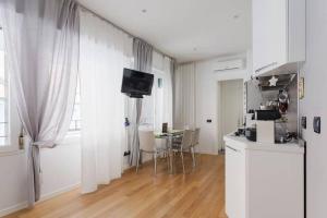 Sala de estar blanca con mesa y TV en Delizioso bilocale in Bocconi - Porta Romana en Milán