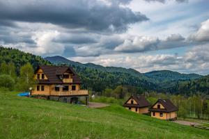 un grupo de casas en una colina en un campo en Krzywy Zakątek - Jaworzynka en Cisna