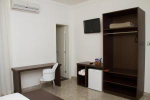 um quarto com uma cama, uma secretária e uma cadeira em Santorini Hotel em Guanhães