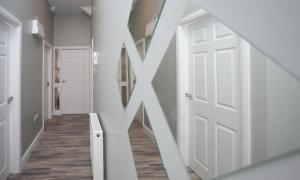 a hallway with white doors and wood floors at University Road Apartments in Belfast