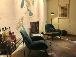 a room with three green chairs and a table and bottles at Alpenloge Design Hotel in Scheidegg