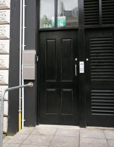 a black door on the side of a building at University Road Apartments in Belfast