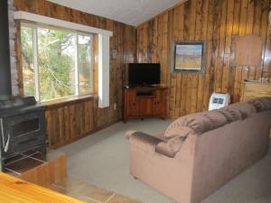 sala de estar con sofá y TV en The Remington Cabin, en Wapiti