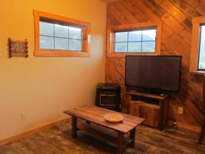 a living room with a tv and a wooden wall at Mountain Man Cabin in Wapiti