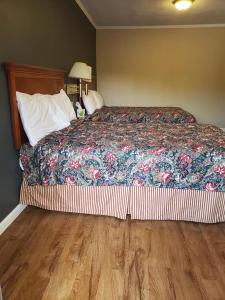 a bed in a bedroom with a wooden floor at Pacific Motel in Gridley