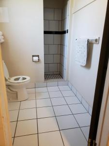 a bathroom with a toilet and a tiled floor at Pacific Motel in Gridley