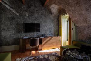 a living room with a desk with a television on a wall at Vila Foz Hotel & SPA - member of Design Hotels in Porto