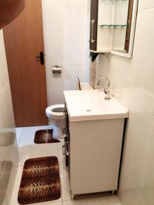 uma casa de banho com um lavatório branco e um WC. em Recanto Shambala em São Tomé das Letras