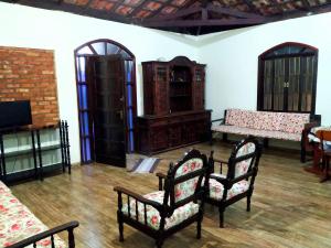 uma sala de estar com cadeiras e mesas e uma televisão em Recanto Shambala em São Tomé das Letras