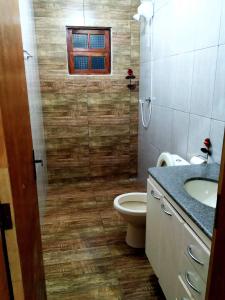baño con aseo y lavabo y ventana en Recanto Shambala, en São Thomé das Letras