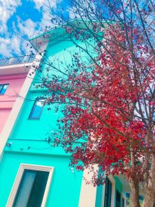 un árbol con hojas rojas delante de un edificio azul en Tongxin Homestay, en Puli