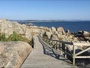 a wooden boardwalk leading to the ocean with rocks at O Pazo in O Grove