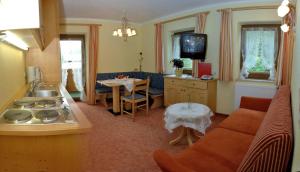 kuchnia i salon z kanapą i stołem w obiekcie Pension und Apartments Landhaus Marie w mieście Leutasch