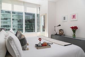 a white bedroom with a white bed and a window at Botticelli Tower By The Local Way in Mexico City