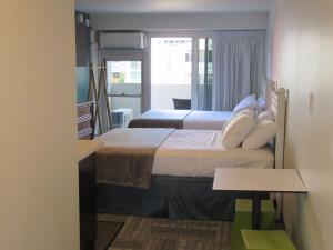 a bedroom with two beds and a table in a room at Waikiki Central Hotel - No Resort Fees in Honolulu
