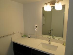 a bathroom with a sink and a large mirror at Waikiki Central Hotel - No Resort Fees in Honolulu