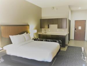 um quarto com uma grande cama branca e uma cozinha em Hotel Glenpool em Glenpool