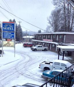 a snow covered street with cars parked in front of a motel at Gold Pan Motel in Quesnel