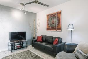 a living room with a black leather couch and a flat screen tv at CitySide Apartment - 2 Bedroom with Private Courtyard in Darwin