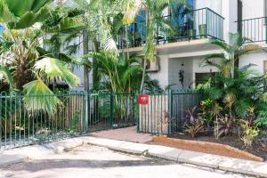 a gate in front of a building with palm trees at CitySide Apartment - 2 Bedroom with Private Courtyard in Darwin