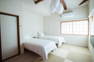 two beds in a white room with a window at Vacation House Tennoji 168, Osaka in Osaka