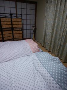 a bed with a polka dot comforter in a bedroom at Japanese Style Inn Dohzen Miwa in Niimi