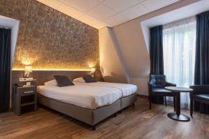 een hotelkamer met een bed, een bureau en een stoel bij Best Western Hotel Baars in Harderwijk