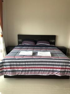 a bed with two pillows and a striped blanket at Pakham Gardens Resort in Prakham