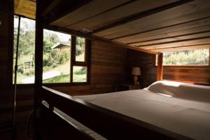 El EncanoにあるHermosa Cabaña en La Cocha-Finca INDIANAの窓付きの客室の大型ベッド1台分です。