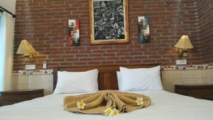 a bed with a blanket and flowers on it at Eliska Sari Bungalows Sumberkima in Pemuteran