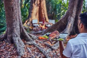 a man is holding a plate of food in a forest at Taj Exotica Resort & Spa, Andamans in Havelock Island