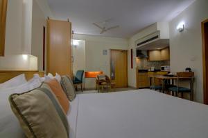 a bedroom with a white bed and a kitchen at Tristar Serviced Apartments in Bangalore