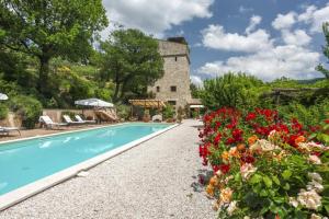 a house with a swimming pool and flowers at Torre del Falco in Spoleto