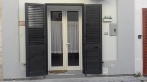 drzwi z czarnymi okiennicami na domu w obiekcie appartamento Manzoni w mieście Porto Cesareo
