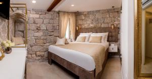 ein Schlafzimmer mit einem großen Bett und einer Steinmauer in der Unterkunft Jupiter Lux Rooms in Split