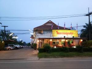 a restaurant with a sign on the side of a street at Poon Suk Hotel Kabin Buri in Kabin Buri