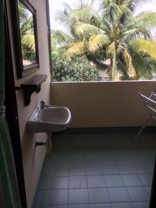 a bathroom with a sink and a palm tree at Poon Suk Hotel Kabin Buri in Kabin Buri